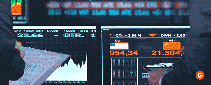 Two suited men examining stock market information on a computer screen, demonstrating a collaborative analysis.